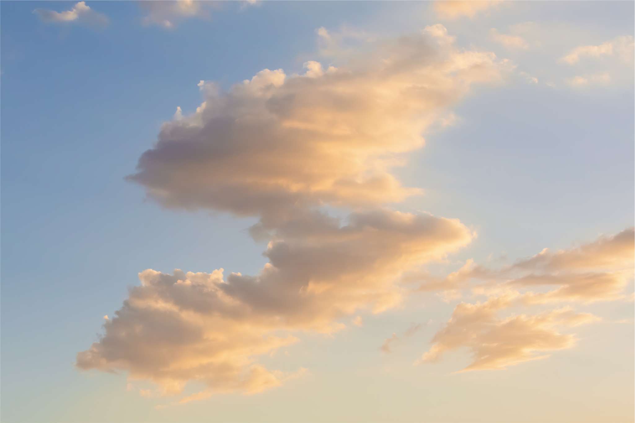 Soft golden clouds in a clear blue sky during sunset.